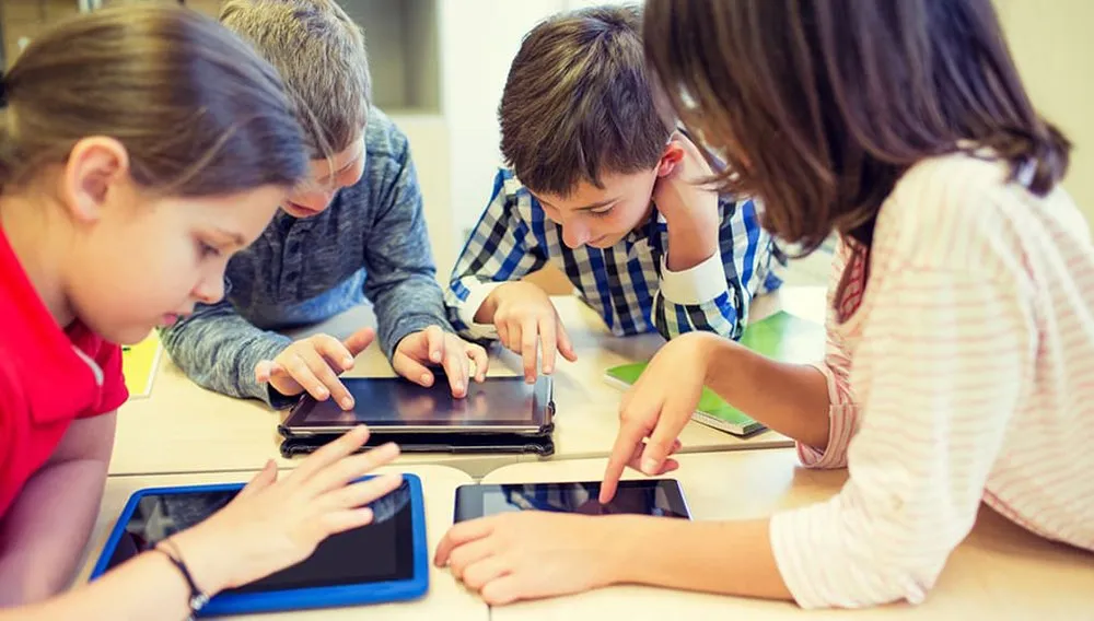 Elementary Students Having Fun Playing Online Games On Tablets Feature Image